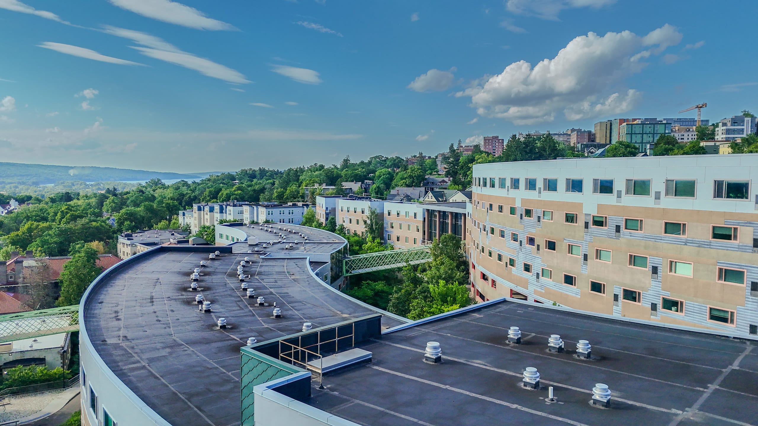 An aerial view of a large multi building apartment complex, photographed from above the rooftops with the surrounding hills and lake beyond.